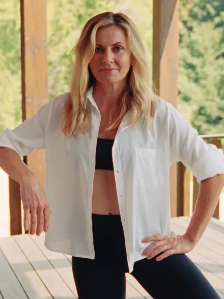 A fitness coach in a white shirt and black leggings on a deck