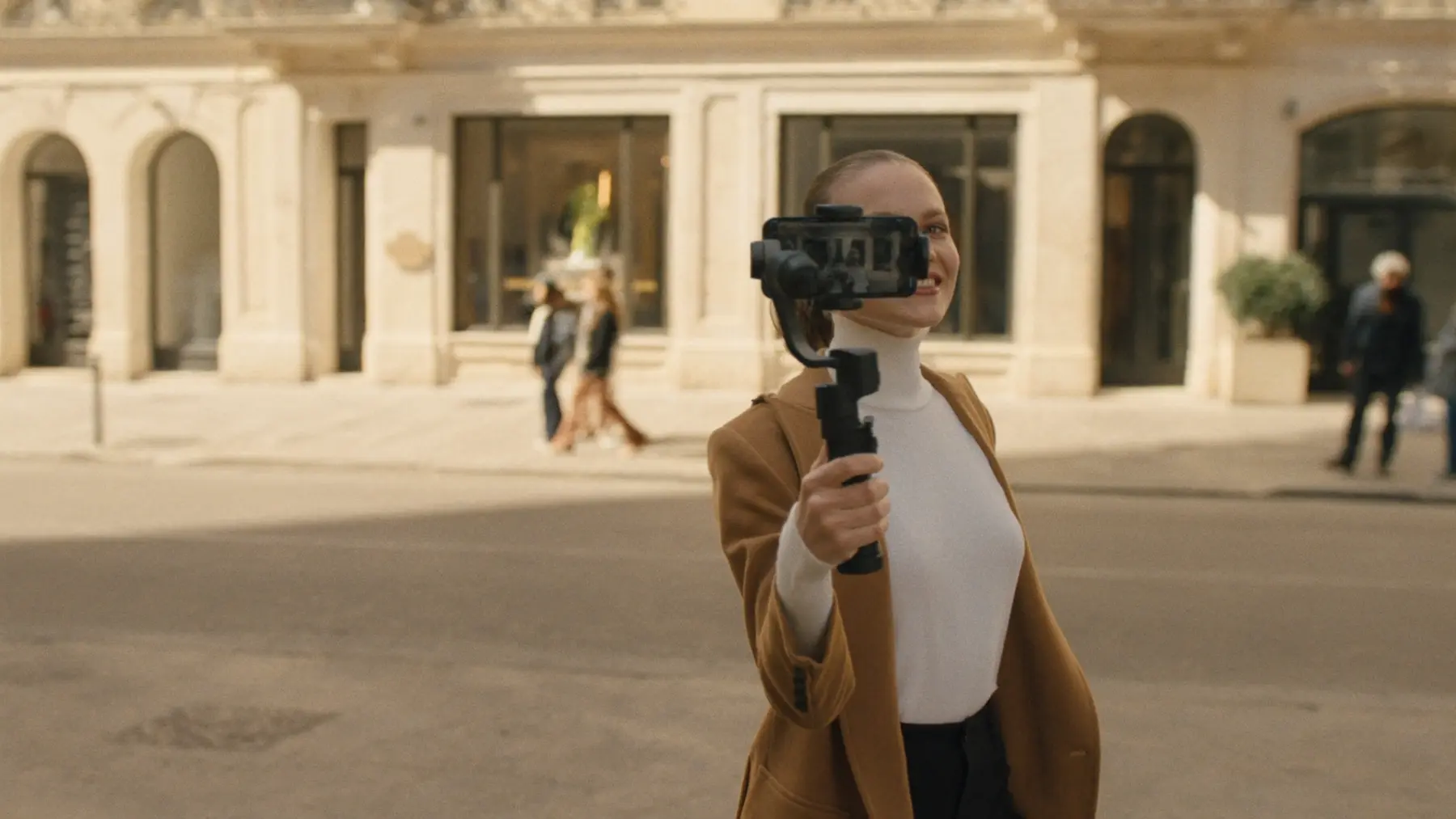 A creator films herself with a phone on a gimbal on a city street