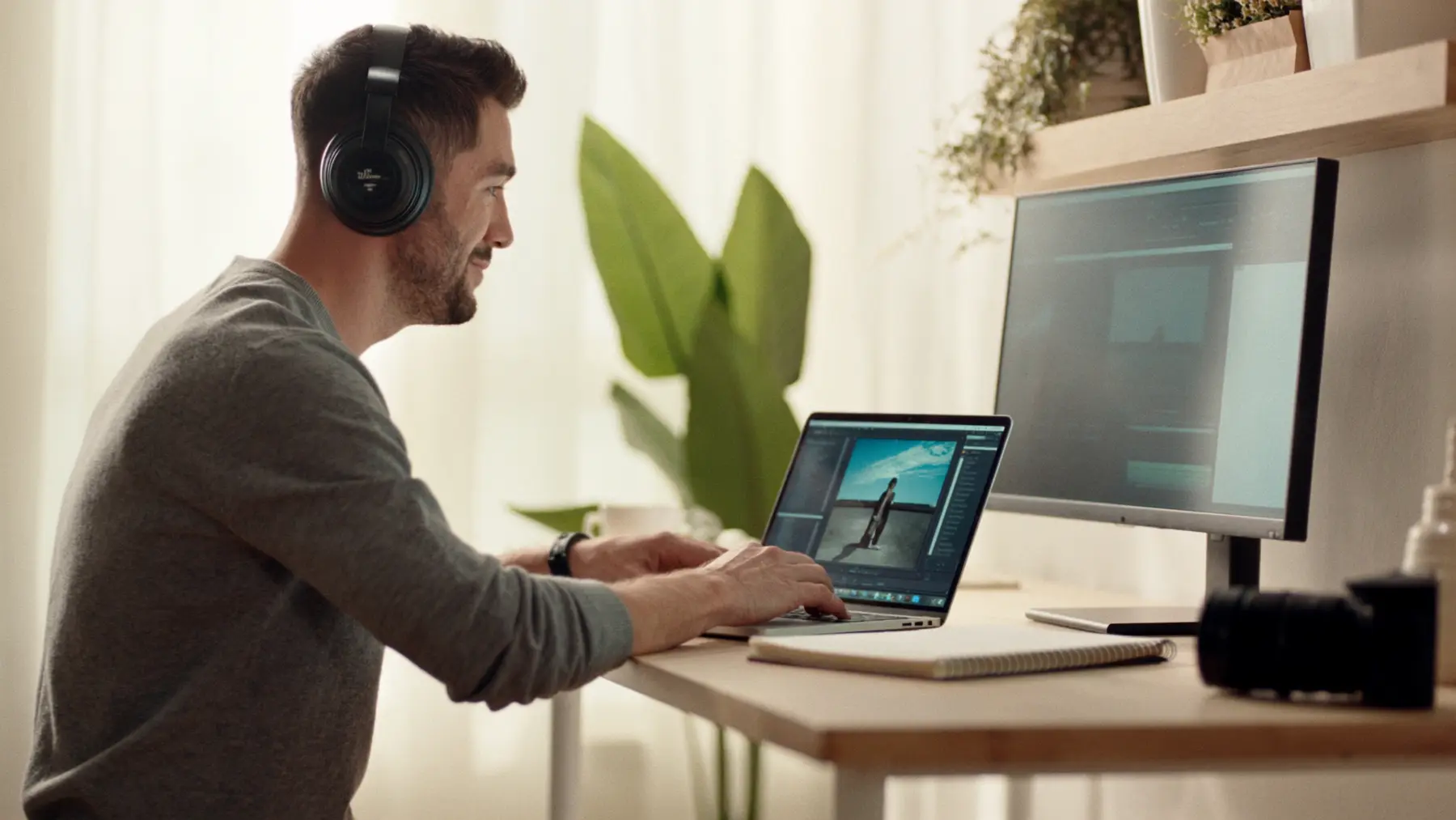 A creator edits a video at a desk with a laptop and headphones