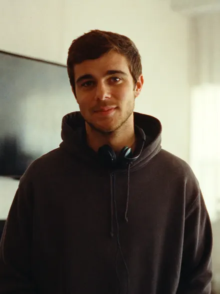 A young man in a dark hoodie with headphones round his neck